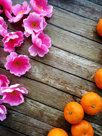 High angle view of artificial flowers and oranges on wooden table