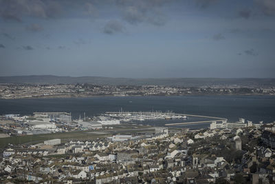 Aerial view of city by sea against sky