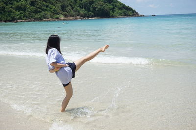 Woman kicking water while standing at beach