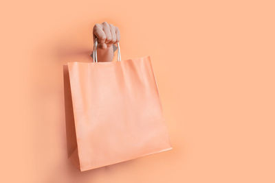 Cropped hand of woman holding gift against yellow background