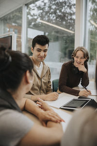 Smiling male and female students studying together at university