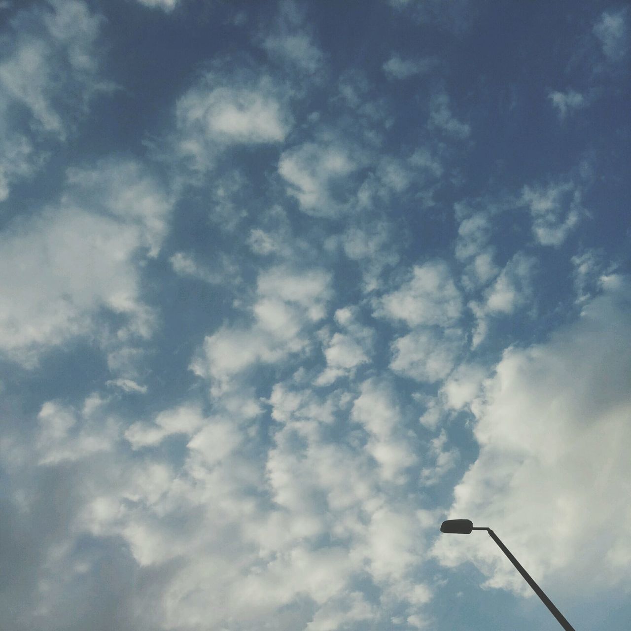 low angle view, sky, cloud - sky, cloudy, nature, beauty in nature, tranquility, cloud, blue, scenics, outdoors, day, no people, street light, power line, tranquil scene, high section, sky only, silhouette, cloudscape