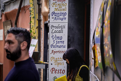 Rear view of woman with text on wall in city