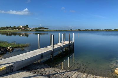 Wooden posts in lake against sky