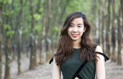 Portrait of smiling young woman standing in forest