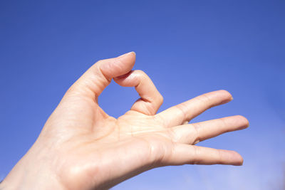 Cropped hand gesturing against blue background