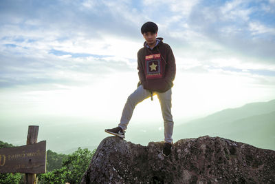 Portrait of man standing on rock against sky