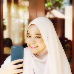 Portrait of smiling young woman using mobile phone