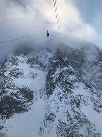 Overhead cable car over snowcapped mountains against sky