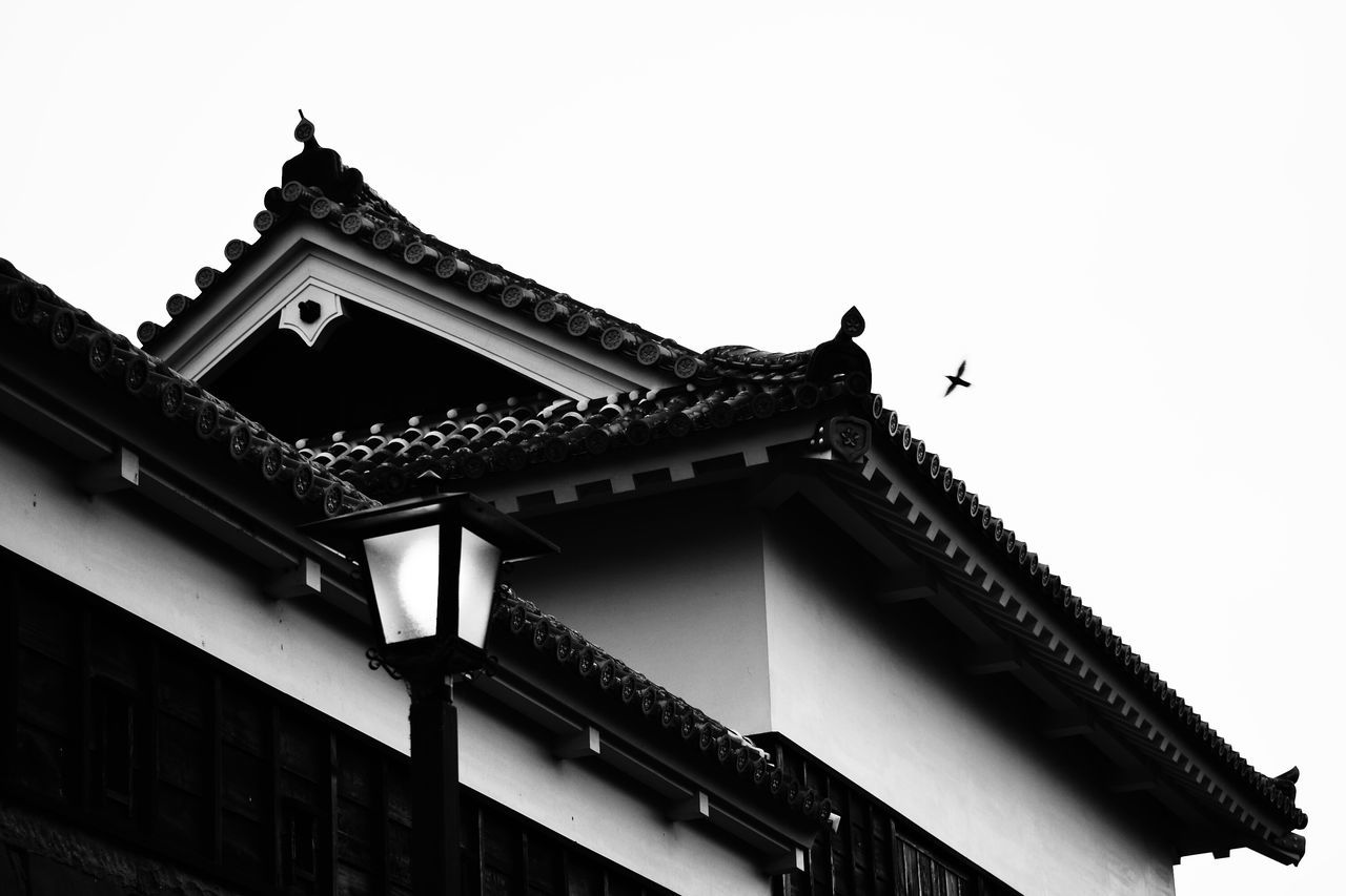 low angle view, architecture, building exterior, built structure, clear sky, bird, animal themes, high section, religion, roof, place of worship, sky, spirituality, outdoors, church, copy space, no people, day, house