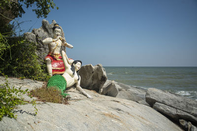 Rear view of woman standing on rock at beach