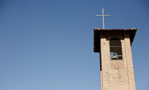 Low angle view of bell tower against clear blue sky