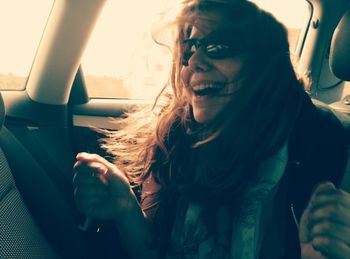 Cheerful young woman traveling in car