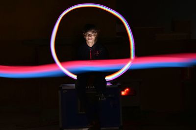 Man standing in illuminated light trails at night