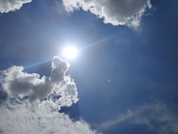 Low angle view of sunlight streaming through clouds