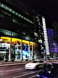 Light trails on road by buildings in city at night