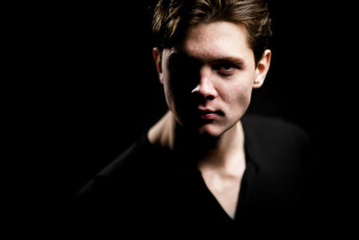 Close-up portrait of mid adult man against black background