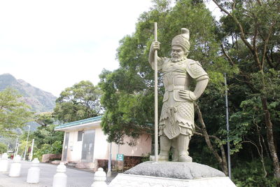 Statue of woman against trees