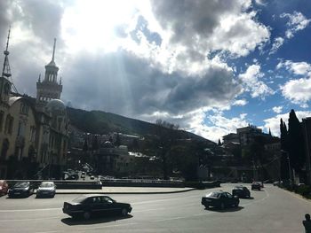 Cars on road in city against sky