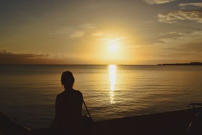 Silhouette man looking at sea against sky during sunset