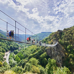 People on mountain against sky on a bridge