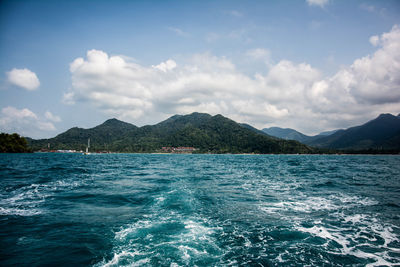 Scenic view of sea by mountains against sky