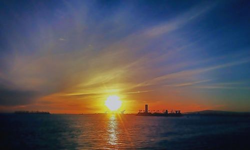 Scenic view of sea against dramatic sky during sunset