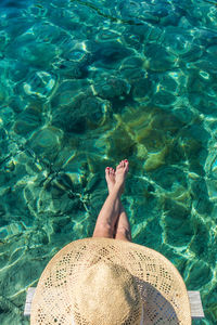 Directly above shot of woman wearing hat sitting by sea