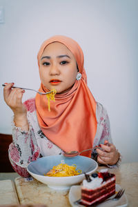 Portrait of smiling young woman having food at home