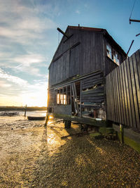 Abandoned house on field against sky during sunset