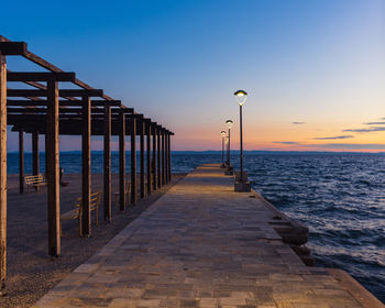 Pier on sea against clear sky at sunset