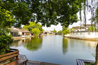 Houses by lake and buildings against sky