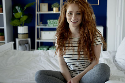 Portrait of smiling young woman sitting on bed