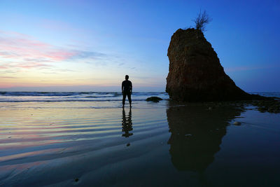 Silhouette man standing on beach against sky during sunset