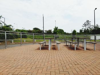 Empty footpath by street against sky