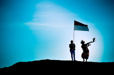 Low angle view of silhouette people walking against blue sky