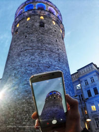 Low angle view of smart phone against sky in city