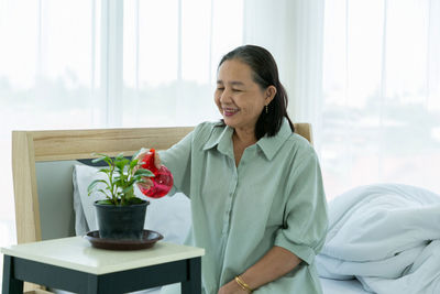 Young woman smiling while standing by potted plant