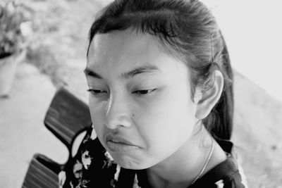 Close-up of thoughtful woman making face while sitting outdoors