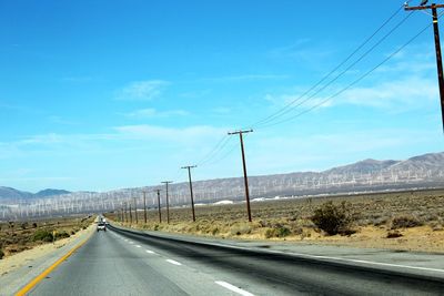 Road by mountains against sky