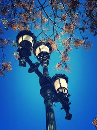 Low angle view of illuminated street light against blue sky