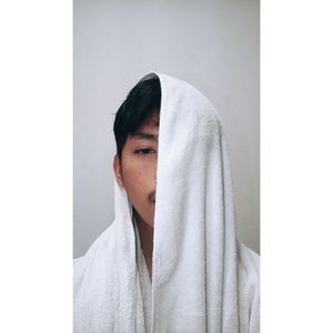 Portrait of man with face covered by towel against gray background