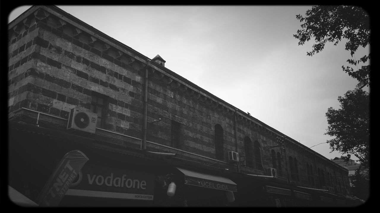 low angle view, architecture, building exterior, transfer print, built structure, text, western script, auto post production filter, sky, communication, building, day, tree, non-western script, outdoors, no people, information, city, transportation, information sign