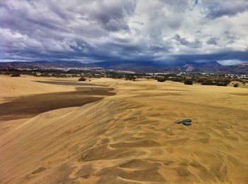Scenic view of desert against cloudy sky