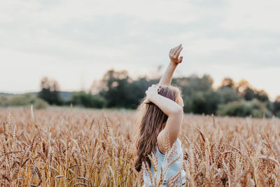 Side view of girl on wheat field during sunset