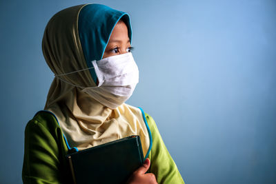 Portrait of man wearing mask against blue background