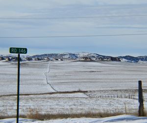 Snow covered landscape against cloudy sky