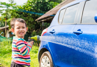 Portrait of cute boy washing car outdoors