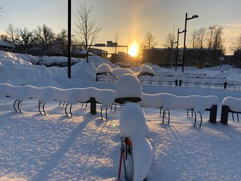 People on snow covered field against sky during sunset