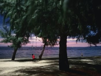 Man standing on beach against sky during sunset